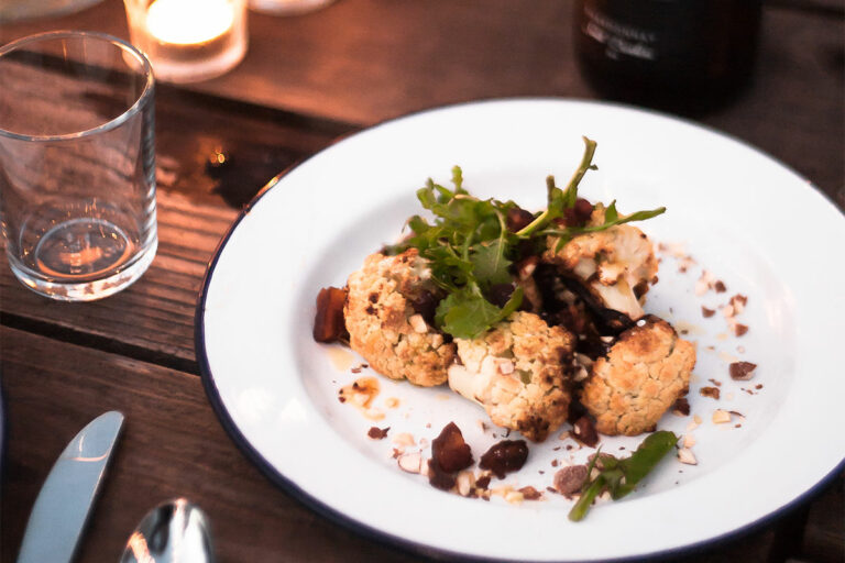 Grilled Cauliflower with Brown Butter and Apricots served on a candle lit dinner table.