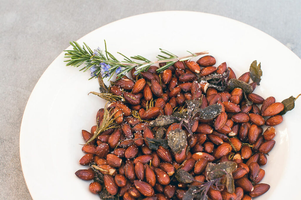 Herby Roasted Almonds decorated with a sprig of rosemary.