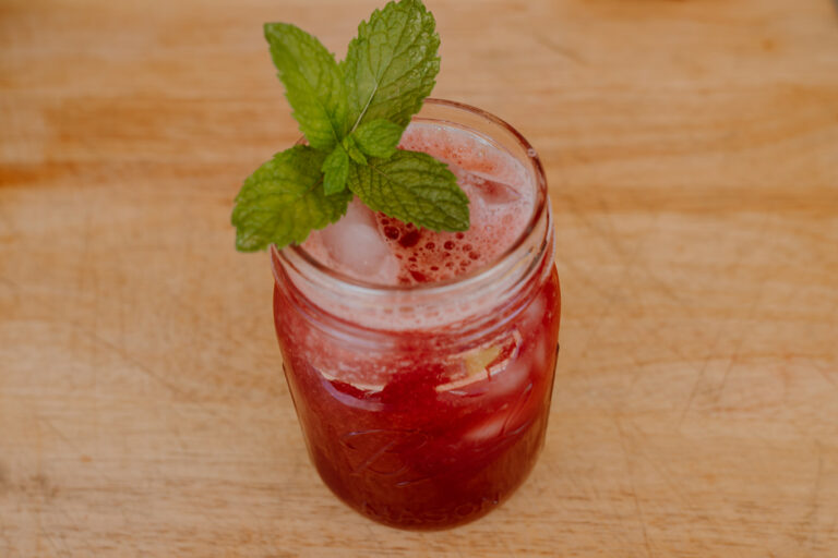 Watermelon and Hibiscus Agua Fresca in mason jar with mint leaf on top.