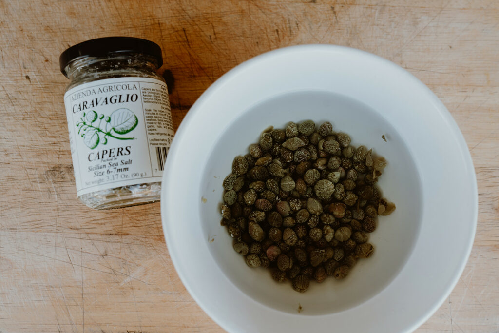 Soaking capers to remove the excess salt.