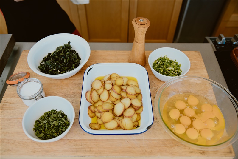 Kale, parsley, potato, scallions, eggs in separate bowls.