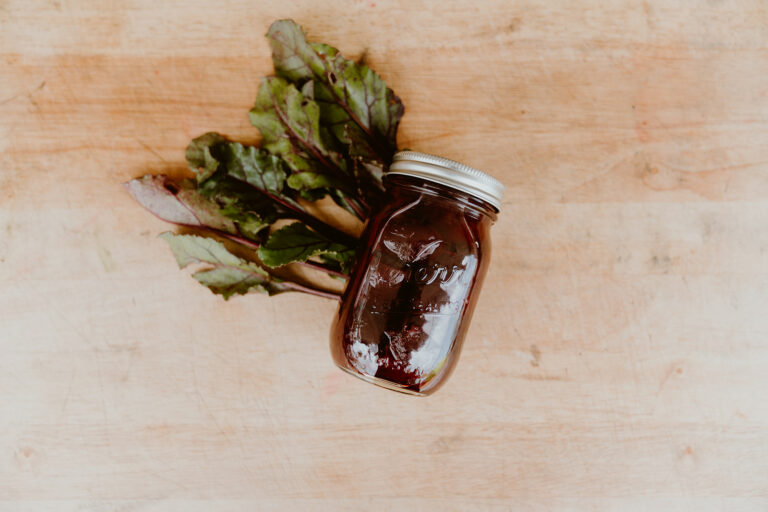 Pickled beets in a jar on the cutting board.