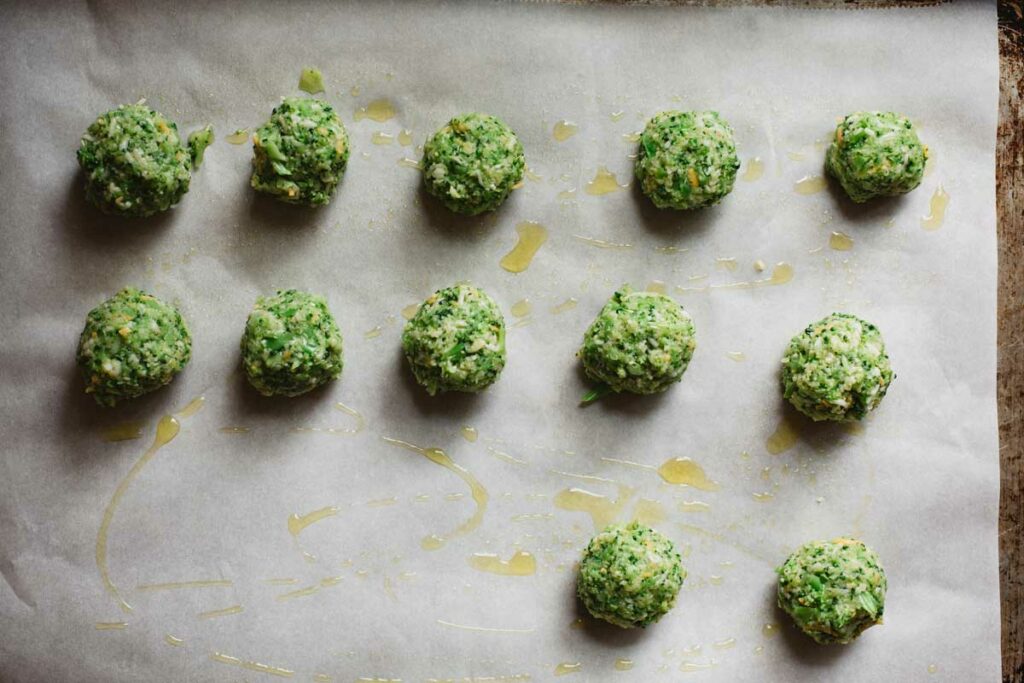 Broccoli balls rolled and placed on baking sheet liner with olive oil.