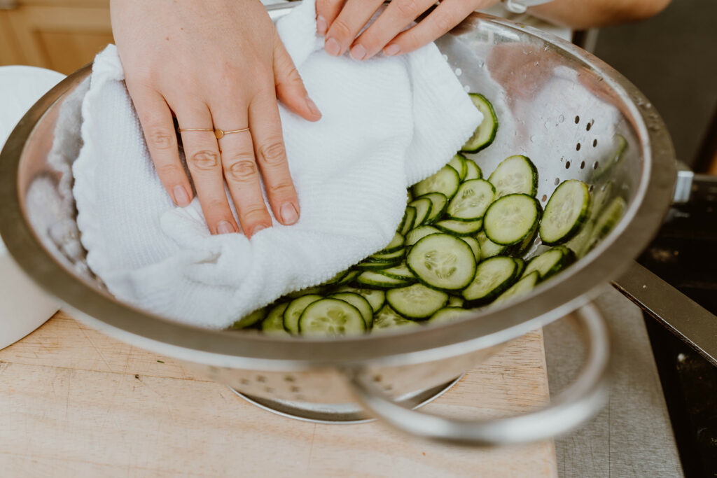 Patting cucumbers dry in colander.