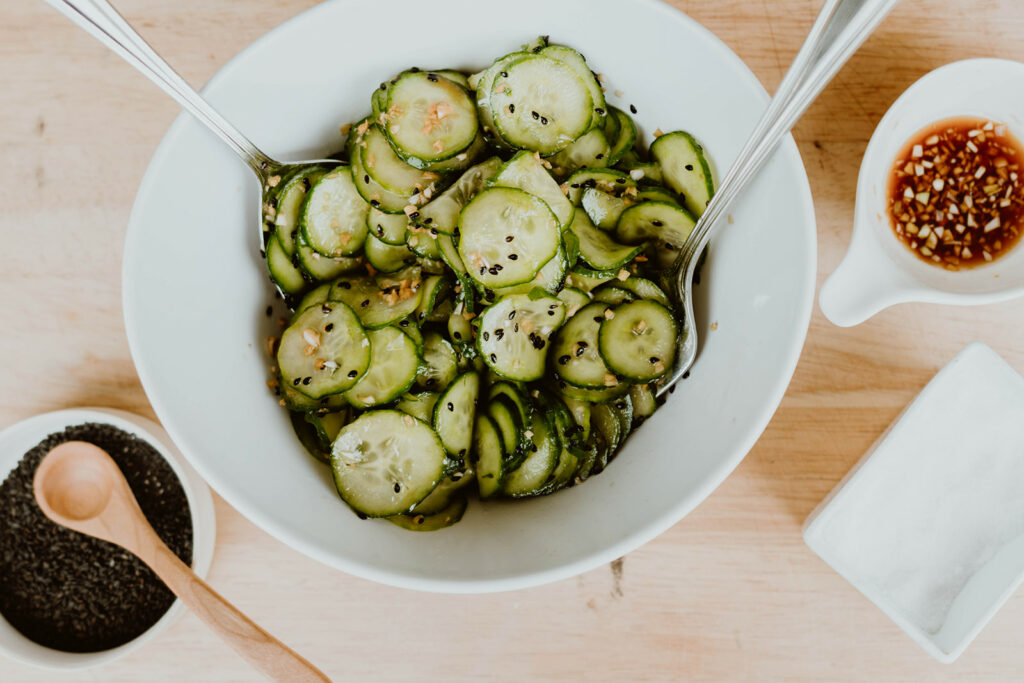 Finished Japanese cucumber salad tossed in a bowl with serving utensils.
