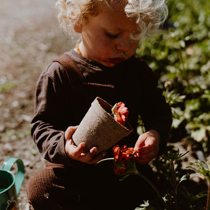 Baby holding flower pot on farm fields.